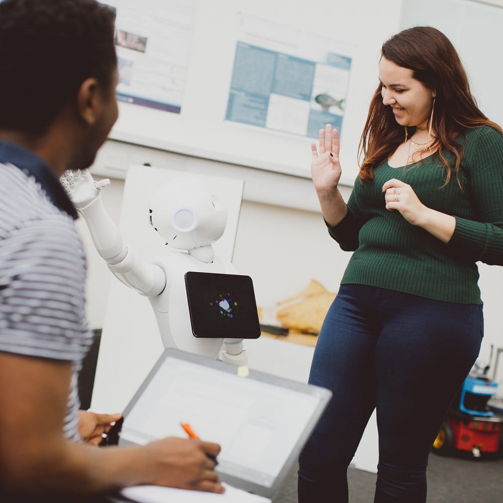 Student and robot waving to each other